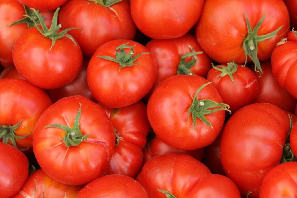 A pile of ripe red tomatoes with green stems